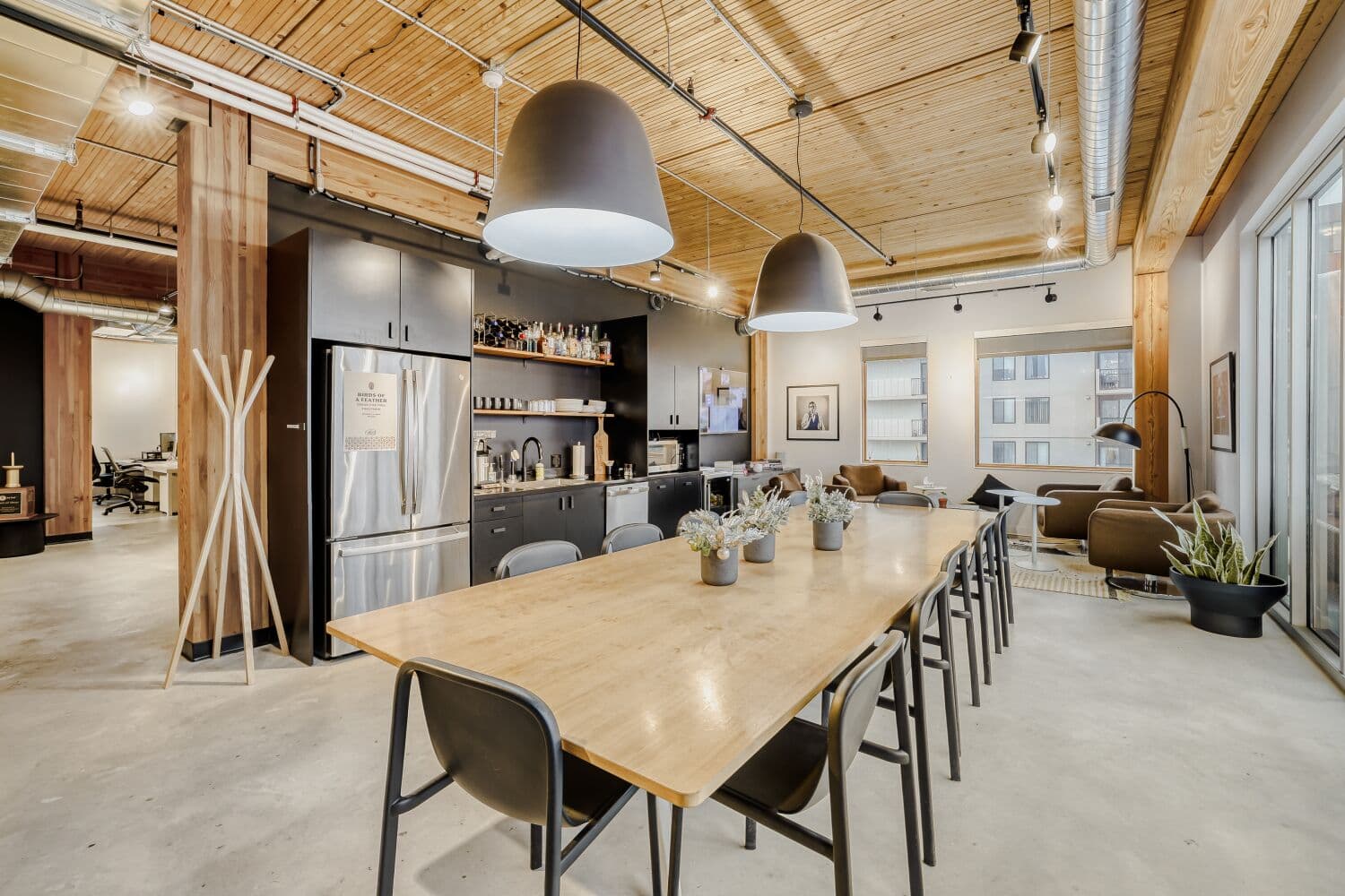 Modern office kitchen and break area with wood ceiling and communal table
